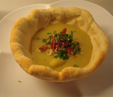 Cremet rodfrugtsuppe med serranoskine og porrer, serveret i brødskåle